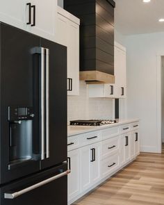 a black refrigerator freezer sitting inside of a kitchen next to white cabinets and drawers