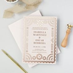 a wedding card with gold foil on it next to a pen and some other items