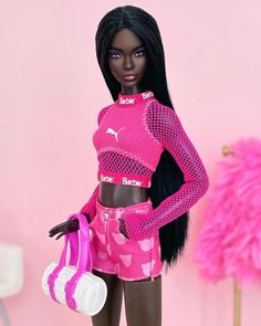 a barbie doll is holding a pink purse and posing for the camera in front of a pink background