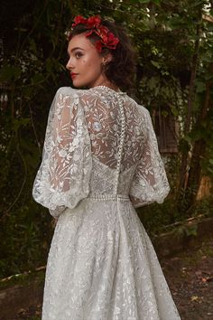 a woman wearing a white wedding dress with flowers in her hair and an open back