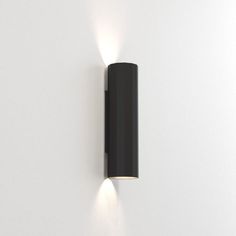 a black wall mounted light on the side of a white wall