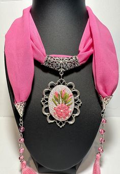 Step into a world of artisanal beauty with this 100% Handmade Embroidered Necklace, featuring a stunning stainless silver-plated chain that enhances the elegance of this wearable work of art. 🌟 Key Features 🌟 ✨ Unparalleled Craftsmanship: Each necklace is lovingly handcrafted, ensuring that every piece is a unique and exquisite creation. Women's scarf necklace features on soft infinity loop scarf with jewelry and accessory. ✨ Intricate Embroidery: The pendant boasts intricate, detailed embroidery, a testament to our commitment to creating wearable masterpieces. ✨ Versatile Beauty: Perfect for everyday wear or special occasions, this necklace infuses your style with timeless grace. ✨ Customizable: Personalize your necklace by choosing your preferred embroidery colors or patterns (contact Traditional Embroidered Jewelry For Gifts, Traditional Silver Embroidered Jewelry, Embroidered Necklaces For Gifts, Elegant Handmade Necklaces For Gifts, Traditional Pink Embroidered Jewelry, Pink Embroidered Wedding Jewelry, Artisan Embroidered Jewelry For Gift, Pink Embroidered Jewelry As A Gift, Embroidered Necklace