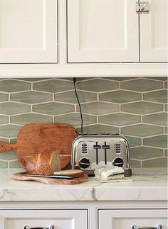 a toaster, knife and bread are on the counter in front of white cabinets