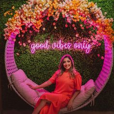 a woman sitting on a chair in front of a flower wall with the words good vibes only