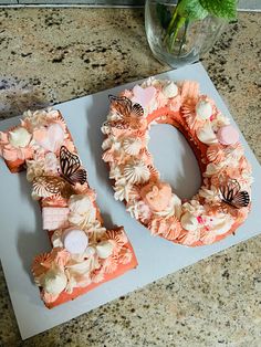 a cake shaped like the letter d on top of a table with flowers and butterflies