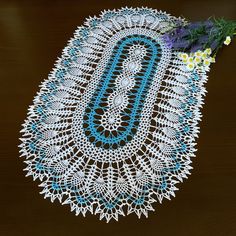 a crocheted doily on a wooden table with flowers in the center and blue letters that spell o