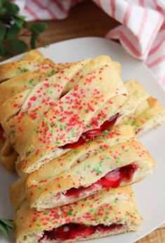 several pastries are stacked on a plate with sprinkles and jelly in them