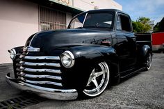 an old black truck parked in front of a building