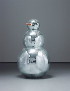 a shiny glass snowman sitting on top of a table next to a gray wall