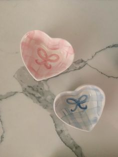 two heart shaped dishes sitting on top of a marble counter