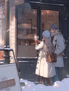 two people standing in front of a bakery looking at their cell phones while it is snowing