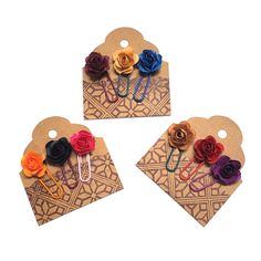 three pieces of paper with different colored flowers on top of each other and two clips attached to them