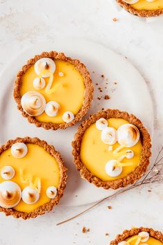 three small pies on a white plate topped with cheese and sea shells next to garlic