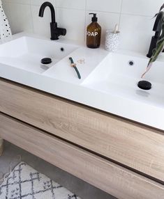 two white sinks in a bathroom with black faucets