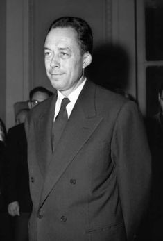 a man in a suit and tie standing next to other people