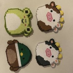 four cross stitch animal magnets sitting on top of a table