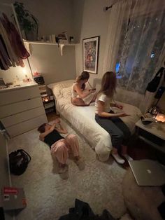 three women sitting on a bed in a bedroom