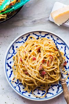 a plate full of spaghetti with meat and cheese on it next to some breadsticks