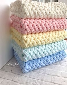 four knitted blankets stacked on top of each other