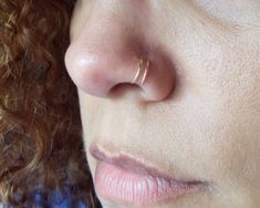 a close up of a woman with a nose piercing on her nose and curly hair