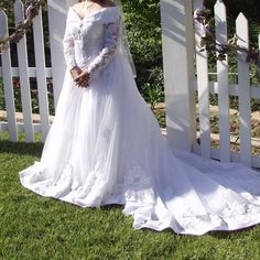 a woman in a wedding dress standing next to a white picket fence