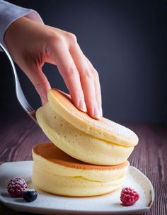 a person is cutting into some pancakes on a plate