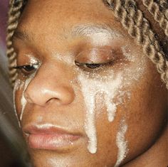 a close up of a person with white powder on her face and hair in braids