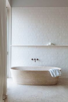 a bath tub sitting in the middle of a bathroom next to a white brick wall