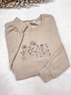 "Embroidered Wildflower Crewneck Sweatshirt, Cute Flower Hoodie. The sweatshirt is a soft spun crewneck and is very soft cotton poly blend, which is so comfy. Embroidered design will be as shown as in the picture. Personalization section: You will need to choose your thread color in this section. Item Description: Unisex Men Sizing Cotton and Polyester Pull On Long Sleeve Crewneck It takes 1-2 weeks to make and process orders for shipping. If you require it sooner, you will need to purchase the Cute Crew Neck Designs, Embroidery Design Sweatshirt, Simple Crewneck Design, Embroidery Crewneck Ideas, Embroidered Crewneck Diy, Cute Embroidered Sweatshirt, Custom Hoodies Ideas Design, Sweatshirt Embroidery Diy, Diy Embroidered Sweatshirt