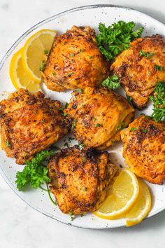 chicken thighs with parsley and lemon on a white plate