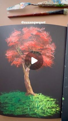 an open book with a drawing of a tree on it and paintbrushes next to it