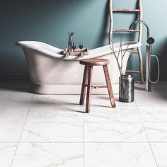 a white bath tub sitting next to a wooden stool