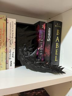 a shelf with several books on it, including one in the shape of a bird