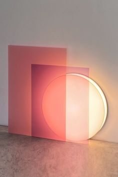 a light that is on in the middle of a room with pink and white walls