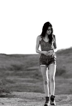 a young woman riding a skateboard down a dirt road in the middle of nowhere