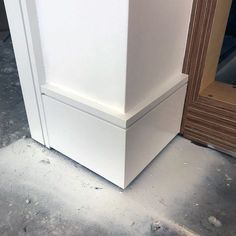 a white refrigerator sitting on top of a floor next to a wooden door and window