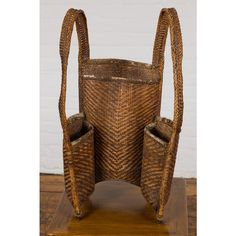 a wicker basket with two handles on a wooden stand