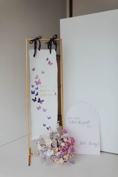 a bouquet of flowers sitting in front of a sign and greeting card with butterflies on it