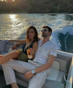 a man and woman sitting on the back of a boat with drinks in their hands