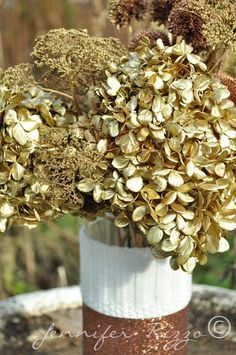 a vase filled with lots of gold colored flowers