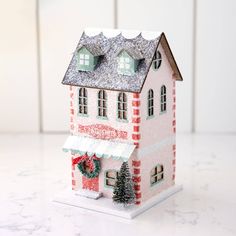 a toy house with a wreath on the front and side of it's roof