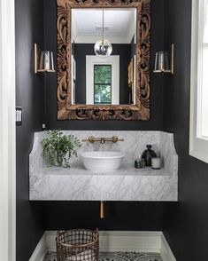 a white sink sitting under a bathroom mirror next to a wooden basket filled with flowers