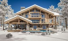 a large wooden house in the middle of winter with snow on the ground and trees around it