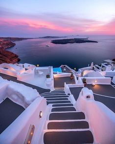 the stairs lead up to an outdoor swimming pool at dusk, overlooking water and land