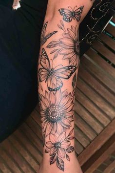 a woman's arm with flowers and butterflies tattooed on the side of her leg