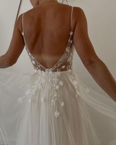 the back of a woman's dress with white flowers on it and sheer tulle