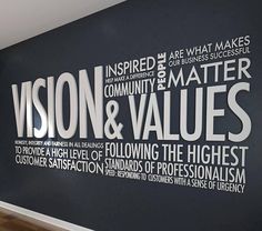 a large black wall with white words on it and wood flooring in front of it