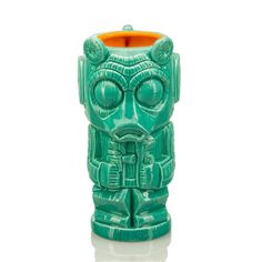 a green ceramic tiki mug with large eyes and an orange rim is shown on a white background