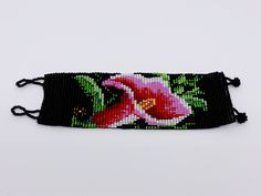 a black beaded bracelet with a pink flower on the front and green leaves on the back