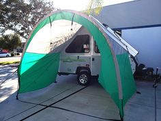 a camper van is parked in front of a building with an awning over it